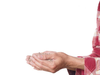 Close-up of man holding hands over white background