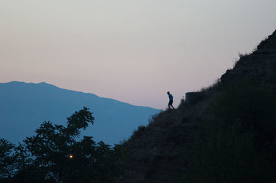 Silhouette man standing on mountain against clear sky