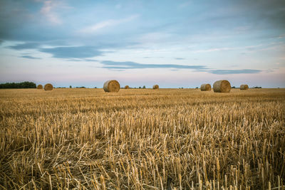 Hay bales on field against sky