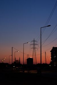 Silhouette electricity pylons against clear sky during sunset