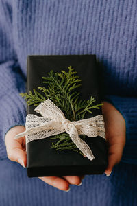 Female hands holding nice gift box. woman giving wrapped in black paper present. cozy gift wrapping