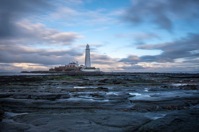 Tower on beach against cloudy sky