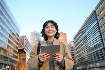 Portrait of young woman using digital tablet in city