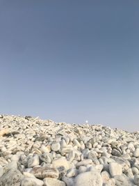 Pebbles on beach against clear blue sky