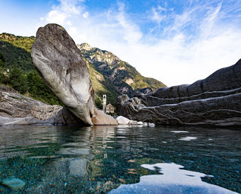 Rock formations in water against sky