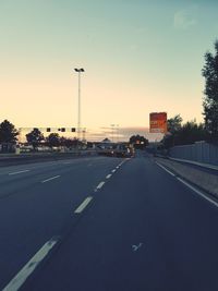 Vehicles on road against sky during sunset