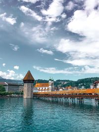 Bridge over river by buildings against sky in city