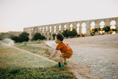 Side view of boy playing with water sprinklers