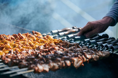 Cropped hand of person preparing food on barbecue grill