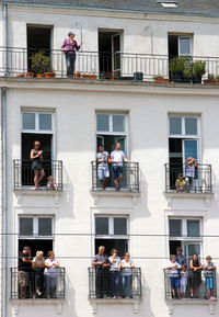 Low angle view of people standing in balcony on sunny day
