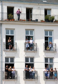 Low angle view of people standing in balcony on sunny day