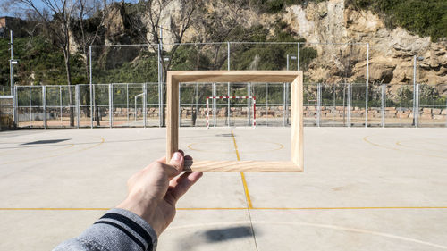 Man holding wooden frame against goal post