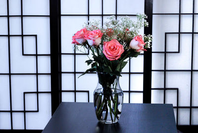 Close-up of roses in vase against window