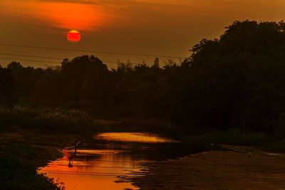 Scenic view of river against sky at sunset