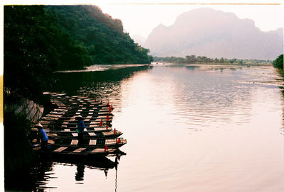 People sitting on lake against clear sky