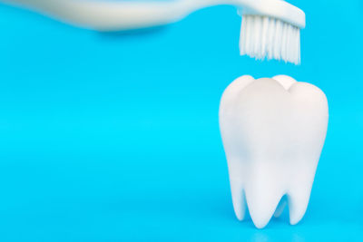 Close-up of toothbrush over dentures against blue background