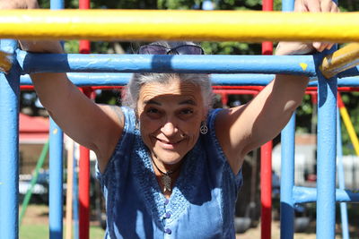 Portrait of mature woman playing on jungle gym in playground