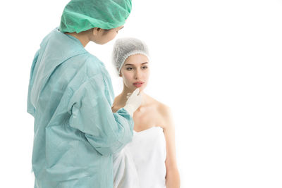 Female doctor examining patient against white background