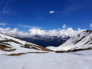 Scenic view of snow covered mountains against blue sky