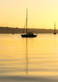 Silhouette sailboats moored on sea against sky during sunset