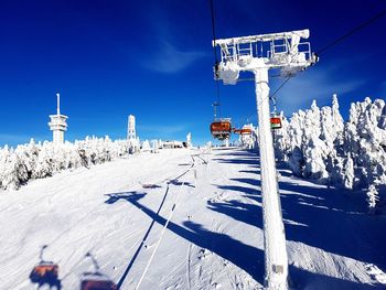 Ski lift over snow covered field against sky