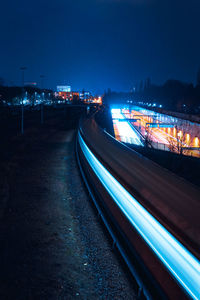 Light trails on road in city against sky at night