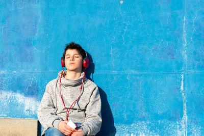 Teenager with headphones listening music while sitting on staircase.