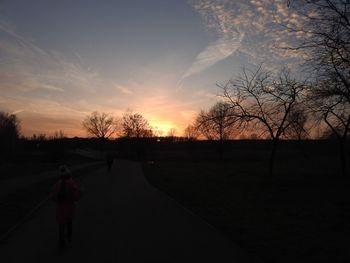 Silhouette of bare trees on landscape against sky