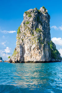 Rock formation in sea against blue sky