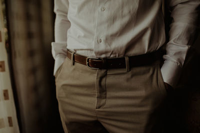 Midsection of man getting dressed while standing at home