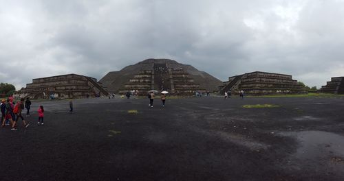 People at town square against cloudy sky