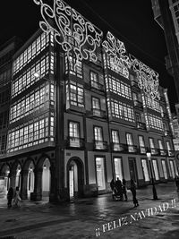 People walking on illuminated building at night