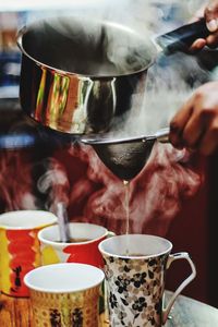 Close-up of person pouring coffee in cup