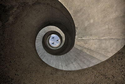 Directly below shot of airplane seen through spiral staircase