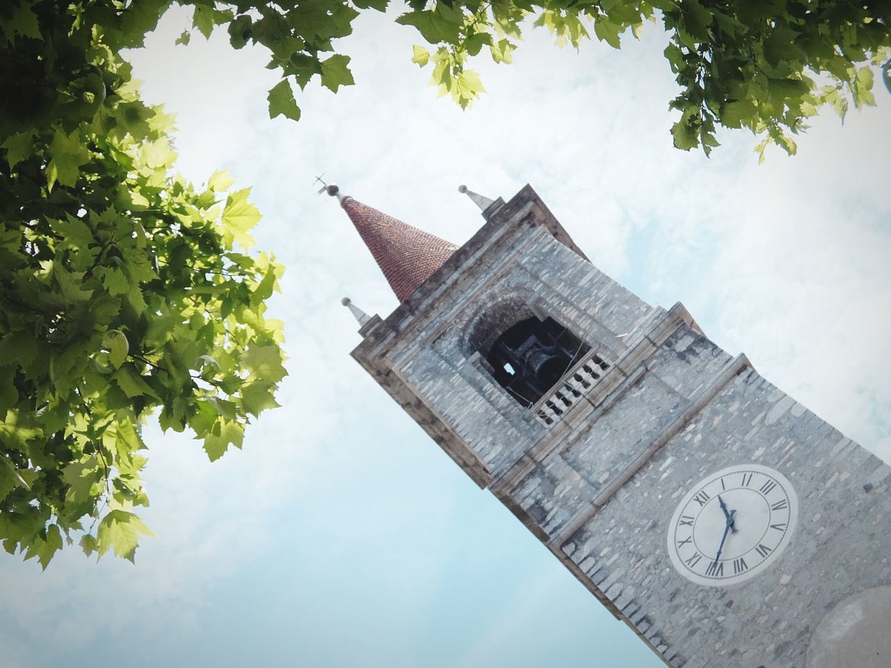 low angle view, building exterior, architecture, built structure, religion, church, place of worship, spirituality, tree, clock tower, sky, tower, cathedral, history, cross, day, steeple, clock