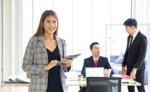 Happy young woman using smart phone at table
