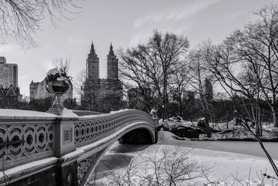 Arch bridge over river against sky in city