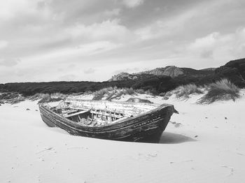 Boat moored on beach against sky