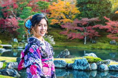 Portrait of smiling woman wearing kimono at park during autumn