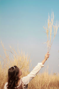 Woman standing by plants on field against sky