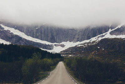 Road amidst snowcapped mountains against sky