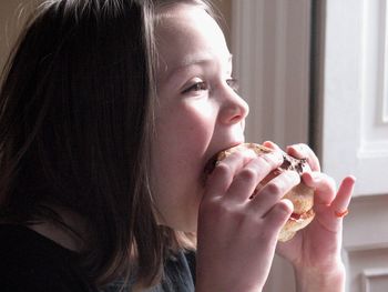 Close-up of girl eating burger at home