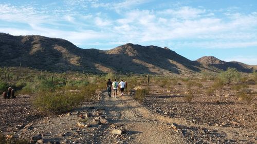 People walking on mountain against sky