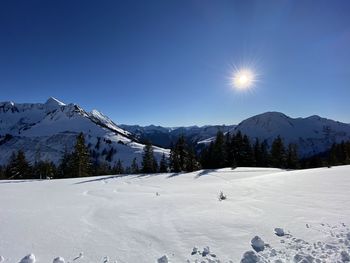 Scenic view of snow covered mountains against bright sun