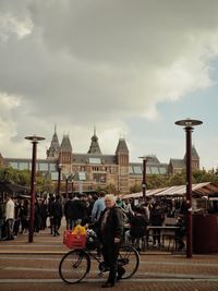 People on bicycle against sky in city