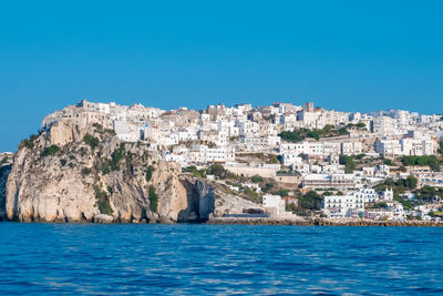 Sea by buildings against clear blue sky