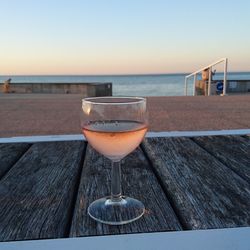 Close-up of drink on table by sea against clear sky