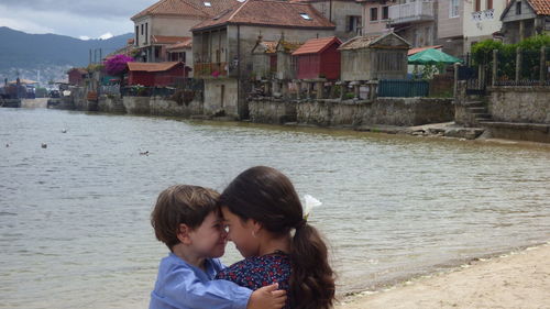 Cute siblings embracing against sea at beach