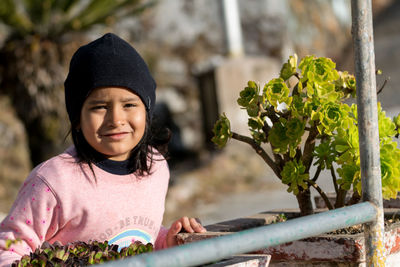 Portrait of young woman standing by railing