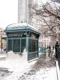 Snow covered footpath by buildings in city